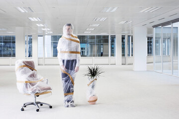 Businessman wrapped in bubble wrap in new office