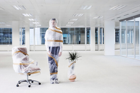 Businessman Wrapped In Bubble Wrap In New Office