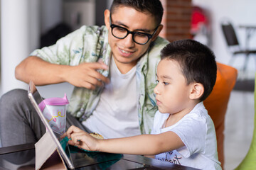 Young man and child watch a tablet at home