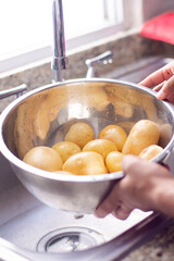 Unrecognizable person washes some potatoes in a bowl