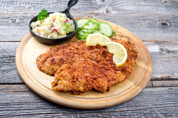 Traditionelles frittiertes Wiener Schnitzel vom Kalb mit Kartoffel und Gurken Salat angeboten als...