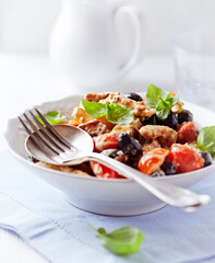 Penne pasta baked with pork tenderloin, cherry tomatoes, black olives and cheese. Close up.