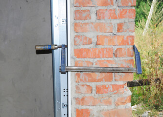 Garage door installation, assembling the door frame to the door lintel with a working tool.