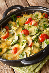 Baked zucchini with cheese and tomatoes close-up in a pan on the table. vertical