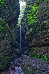 Kleiner Wasserfall mit Bach in einer Schlucht mit grünem Moos im Wald (timeexposure)