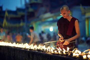 Portrait of buddhist monk lights a candles