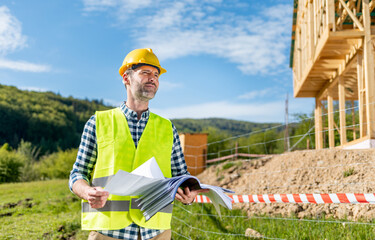 Construction engineer or architect control a construction site of wood frame house