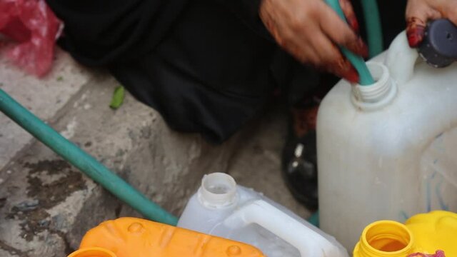 A woman fetching water due to war and siege in the city of Taiz, Yemen