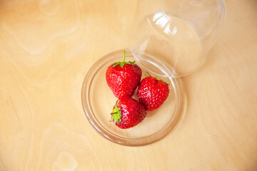 strawberries in a glass bowl on a wooden background.
