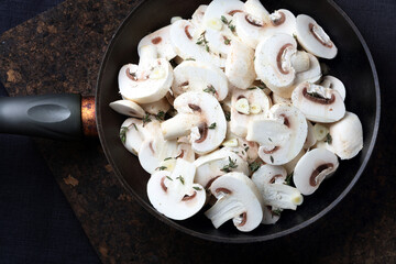 Sliced raw mushrooms with garlic, thyme, salt, ground pepper and vegetable oil in an old black skillet