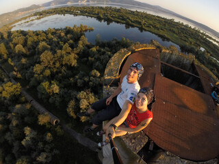 Taking an extreme selfie on top of a ruined tower, life risking extreme sports, happy couple enjoying the panorama 