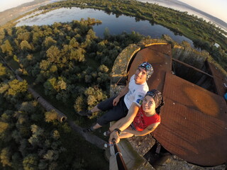 Taking an extreme selfie on top of a ruined tower, life risking extreme sports, happy couple enjoying the panorama 