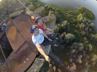 Taking an extreme selfie on top of a ruined tower, life risking extreme sports, happy couple enjoying the panorama 