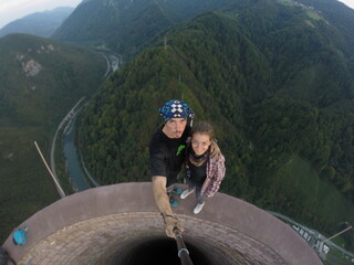 Taking an extreme selfie on top of a ruined tower, life risking extreme sports, happy couple enjoying the panorama 