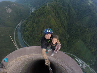 Taking an extreme selfie on top of a ruined tower, life risking extreme sports, happy couple enjoying the panorama 