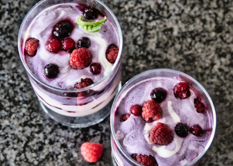 Joghurt, Dessert, Nachtisch im Glas mit Früchten, Beeren und einem Minzblatt