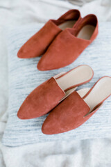 fashionable women’s shoes without heels, mules and loafers, on female legs, a girl in a dress and shoes, resting at home in the bedroom, reading a magazine, trending shoes for advertising