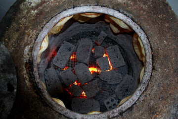Black coal pieces and fire inside caucasian tandir pan