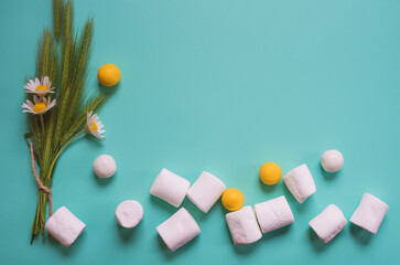 White small pieces of marshmallows and round sweets. Beautiful blue background - concept of advertising sweets.
