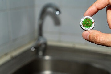Cleaning the water tap. The male hand holds a clogged aerator. Sediment in water