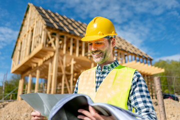 Architect on building site looking at blue prints house plans