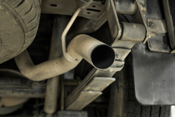 Fototapeta na wymiar Dirty exhaust muffler of a vehicle with tier blur background
