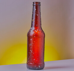 Cold bottle of beer,shot on a white surface,with a yellow and grey gradient background.