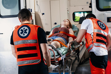Female young victim of the accident lies on a stretcher in an ambulance