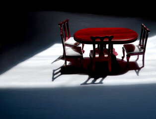 Empty Dollhouse Dining Room Table and Chairs, right of center, casting shadows on dark background