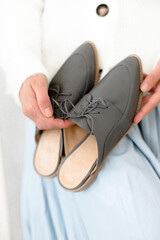 gray stylish and modern women's loafers on a layout, in the hands of a girl, shoes on toes, trendy photos of shoes