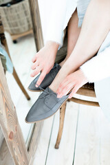 gray stylish and modern women's loafers on a layout, in the hands of a girl, shoes on toes, trendy photos of shoes