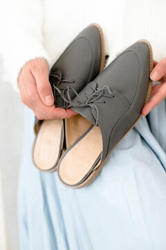gray stylish and modern women's loafers on a layout, in the hands of a girl, shoes on toes, trendy photos of shoes