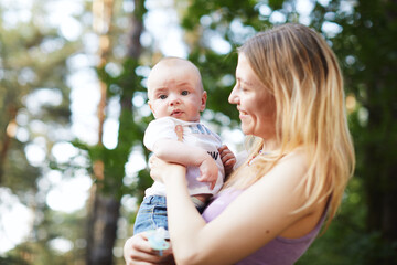 Beautiful blonde mom with he baby in forest,summer time.