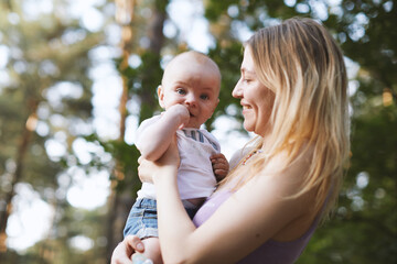 Beautiful blonde mom with he baby in forest,summer time.