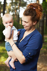 Beautiful blonde mom with he baby in forest,summer time.