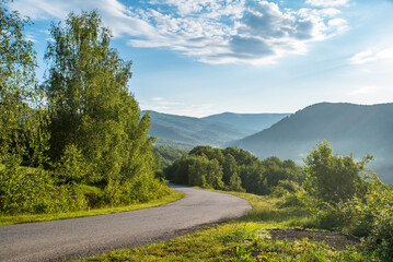 country road leading into green clean ecological mountains. rest in solitude.