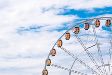 Modern white Ferris wheel against a blue sky with clouds, Attraction for children and tourists, top city view in Krakow, Poland.