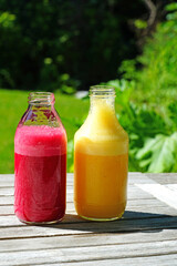 Glass bottles filled with colorful fresh homemade beet and peach smoothies