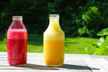 Glass bottles filled with colorful fresh homemade beet and peach smoothies