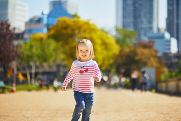 Fototapeta premium Cheerful toddler girl running on a street of Paris, France