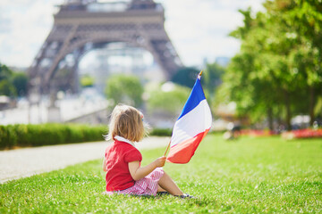 toddler girl with French national tricolor flag near the Eiffel tower in Paris, France