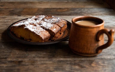 Coffee with milk in a ceramic mug, homemade cupcake in a ceramic bowl on a wooden table.