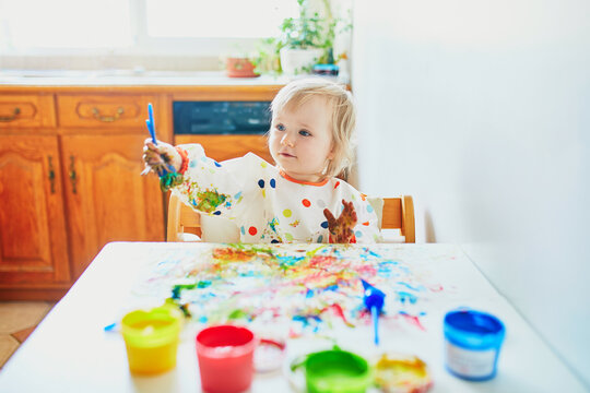 Adorable little girl painting with fingers at home