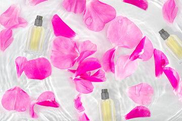 A bottle of perfume in pure waves of water. Flowers and delicate rose petals with drops.