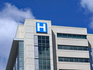large modern building with blue letter H sign for hospital - 358632245