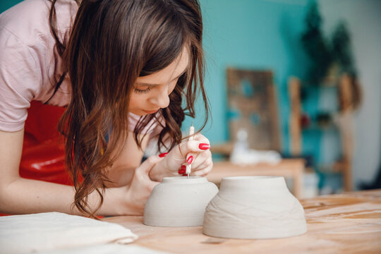 Beautiful potter girl makes pottery for roasting in oven. Concept artist craft, concentration in workplace