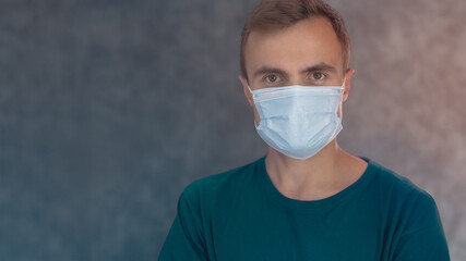 a young man of European appearance stands in a mask against the background of a textured wall in a blur