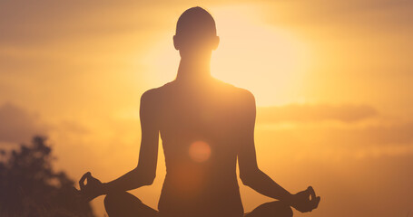 silhouette of a woman meditating in the sunset - Powered by Adobe