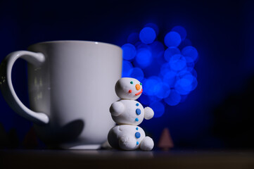 Cute snowman and little Christmas trees made of marshmallows on the background of Christmas lights....