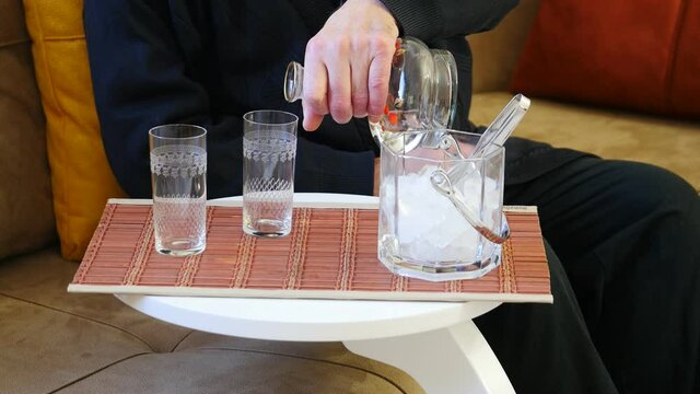 Aged male hands pouring RAKI into the glass from liquor bottle. Arrack is a levantine alcoholic spirit in the anis drinks family. Raki, mastika and ouzo are aniseed flavored drinks, related to arak, m